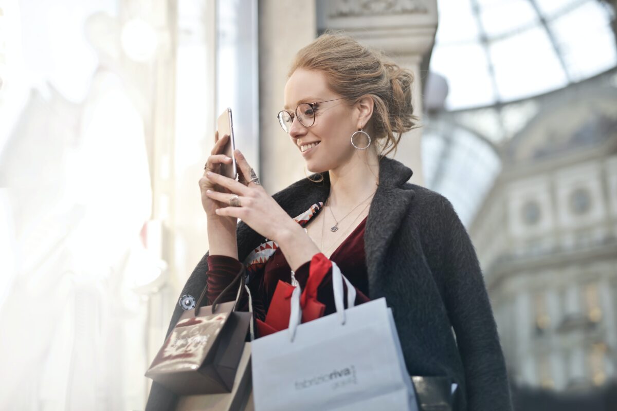 woman holding her phone and shopping bags with high end fashion labels