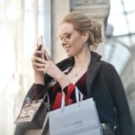 woman holding her phone and shopping bags with high end fashion labels
